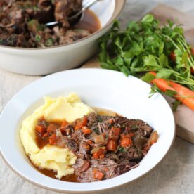 serving stracotto di manzo on a white plate with side dishes