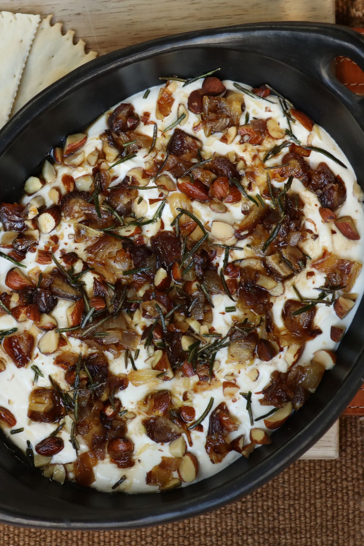 whipped goat cheese dip in a serving bowl topped with dates, shallots, and rosemary