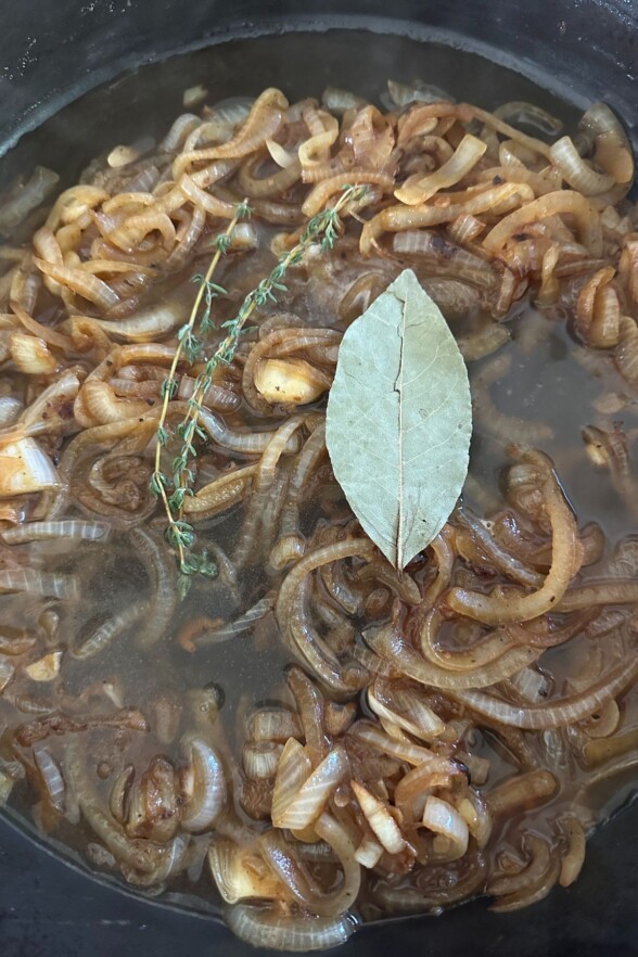 adding bay leaf and thyme to the caramelized onions