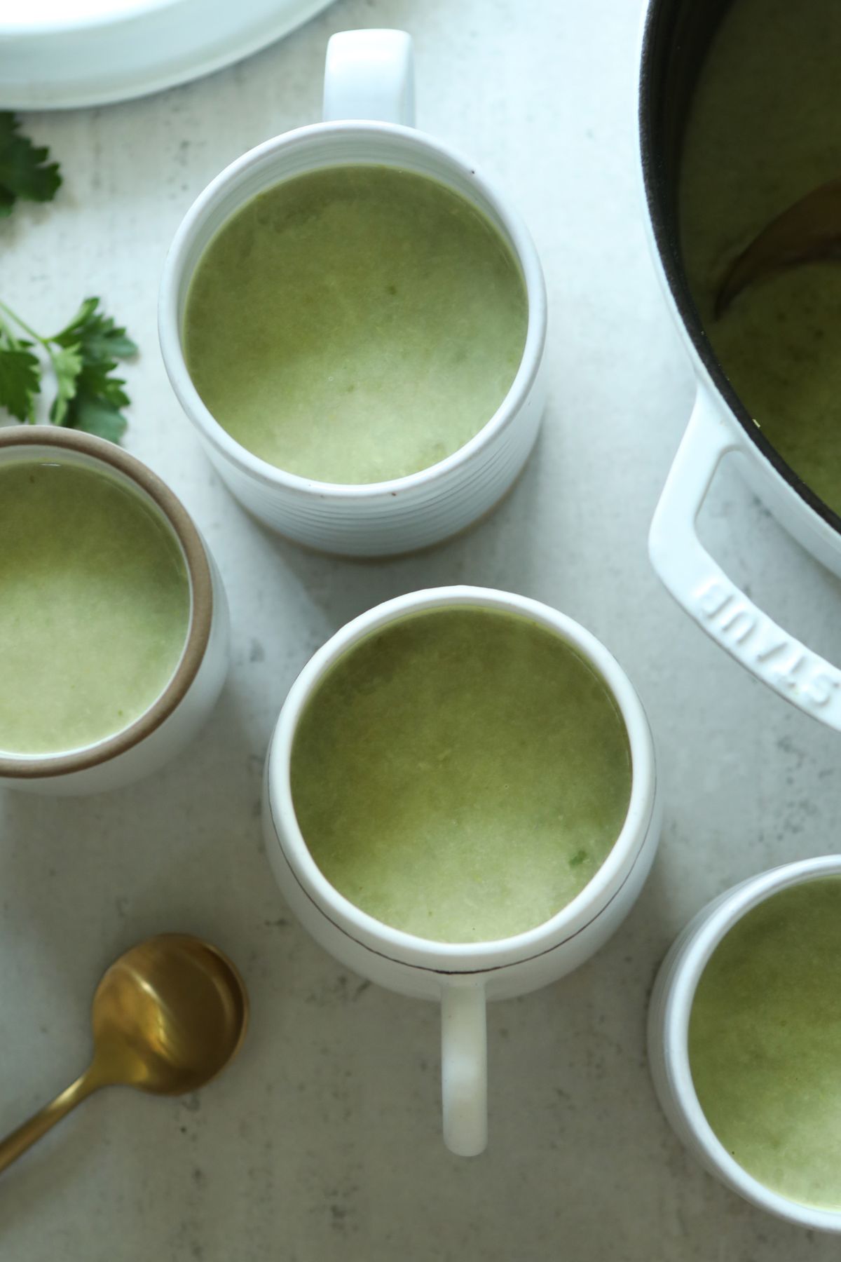 super green soup in mugs on a counter top