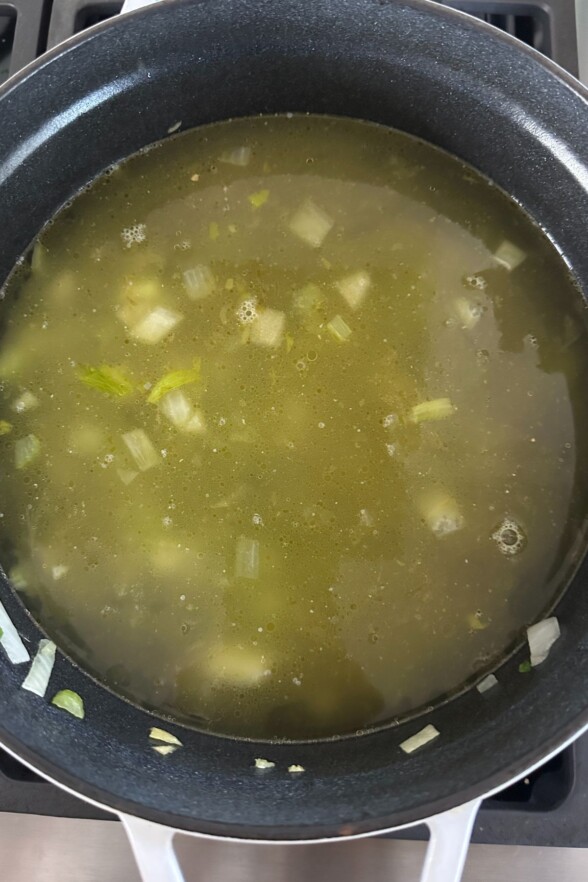 broth poured on top of the cooked veggies in the soup pot