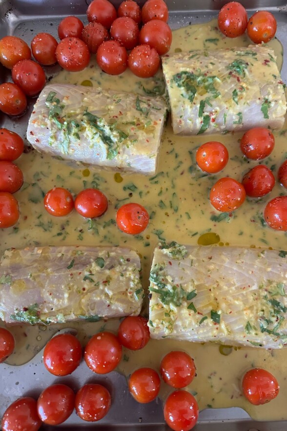 raw fish and tomatoes on a baking sheet 