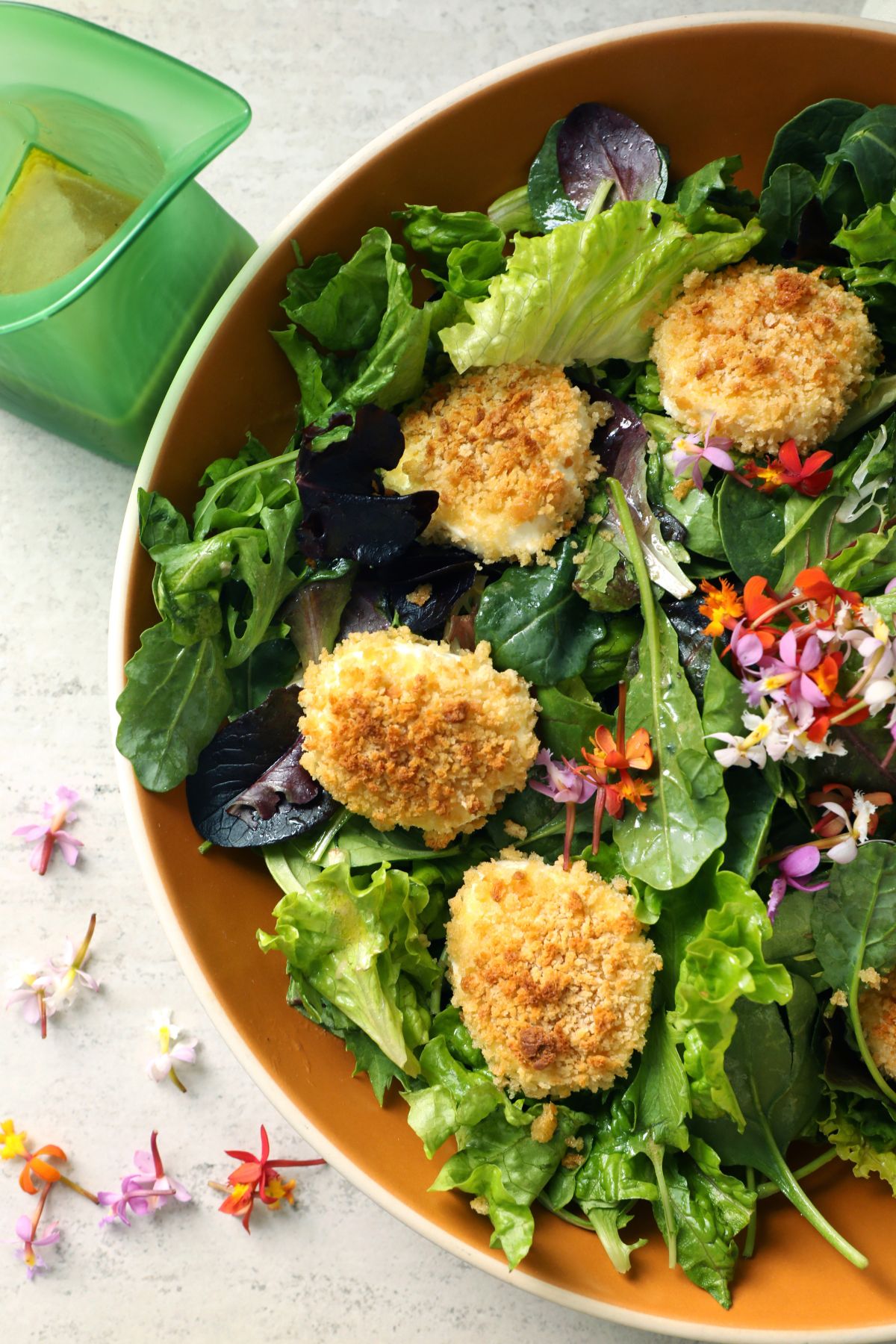 baked goat cheese salad in a salad bowl topped with vinaigrette