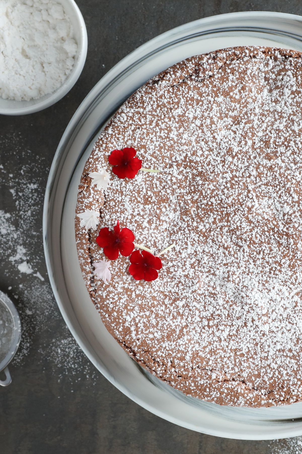 half of a torta caprese topped with dusted powdered sugar and flowers