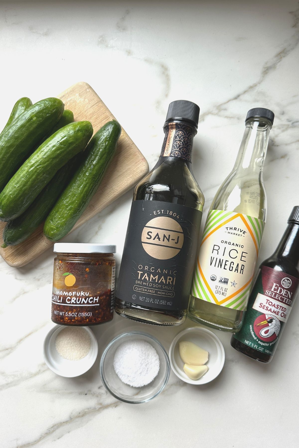 Ingredients for spicy cucumber salad, including cucumbers, garlic, chili oil, and soy sauce
