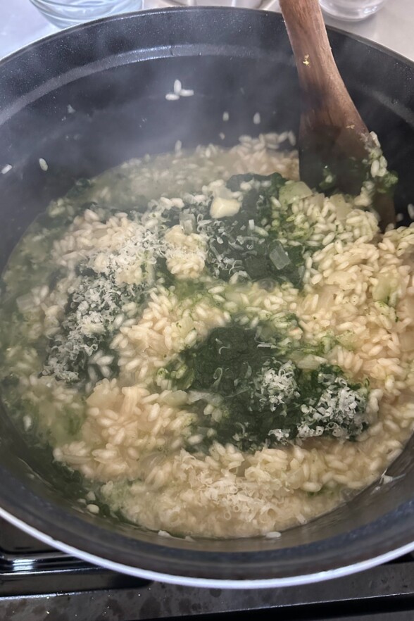 a pot filled with spinach puree, arborio rice, onions, and seasonings