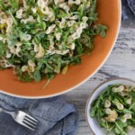 Bowl of arugula pasta salad with zucchini, walnuts, and pepperoncini dressing