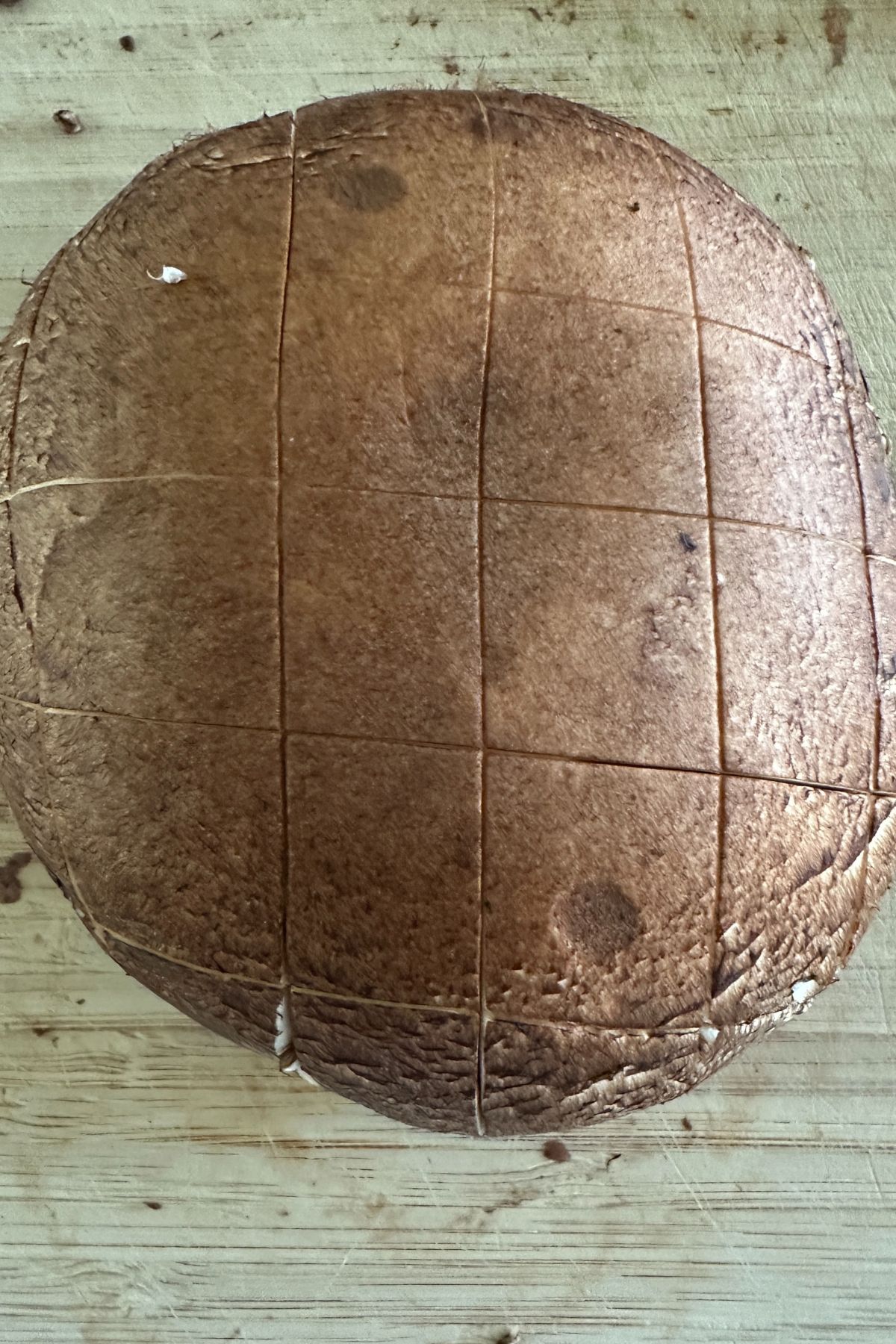 Scored portobello mushroom caps ready for marinating on a wooden board.