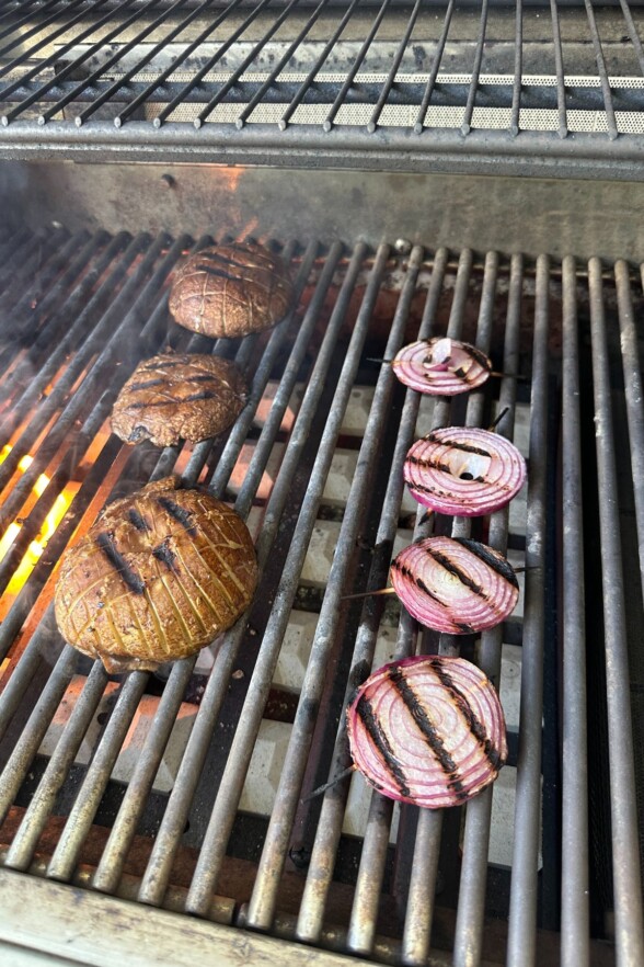 Portobello mushrooms flipped on the grill with visible crosshatch sear and caramelized onions.