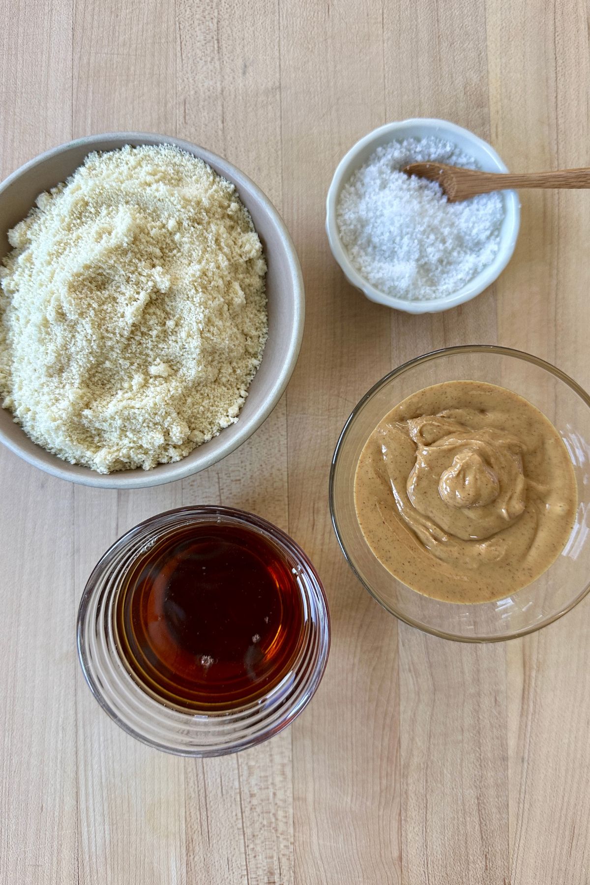 Ingredients for homemade Nutter Butter cookies including almond flour, maple syrup, peanut butter, and flaky sea salt