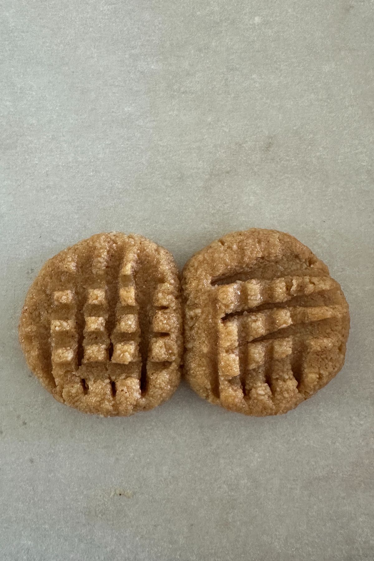 Raw cookie dough balls pressed into peanut shapes on parchment-lined baking sheet