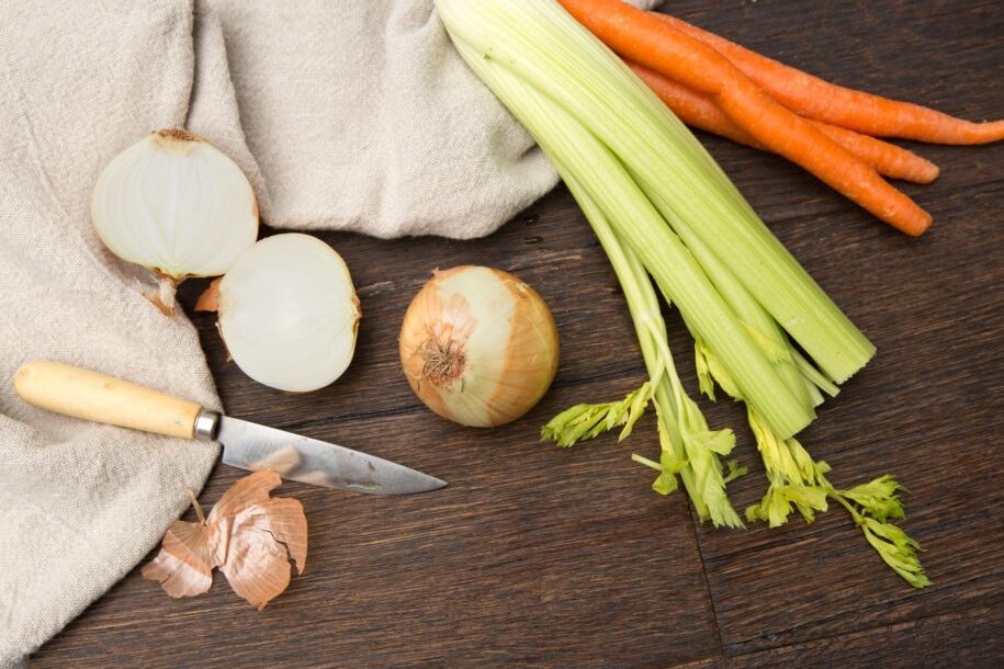 Fresh vegetables and aromatics simmering in chicken stock on the stovetop
