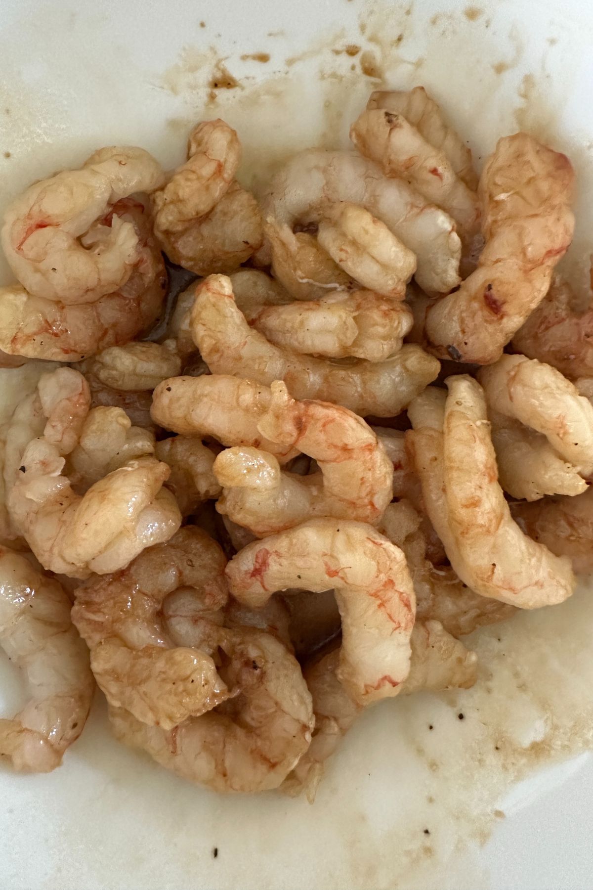 Raw shrimp marinating in a bowl with tamari, arrowroot, and seasonings