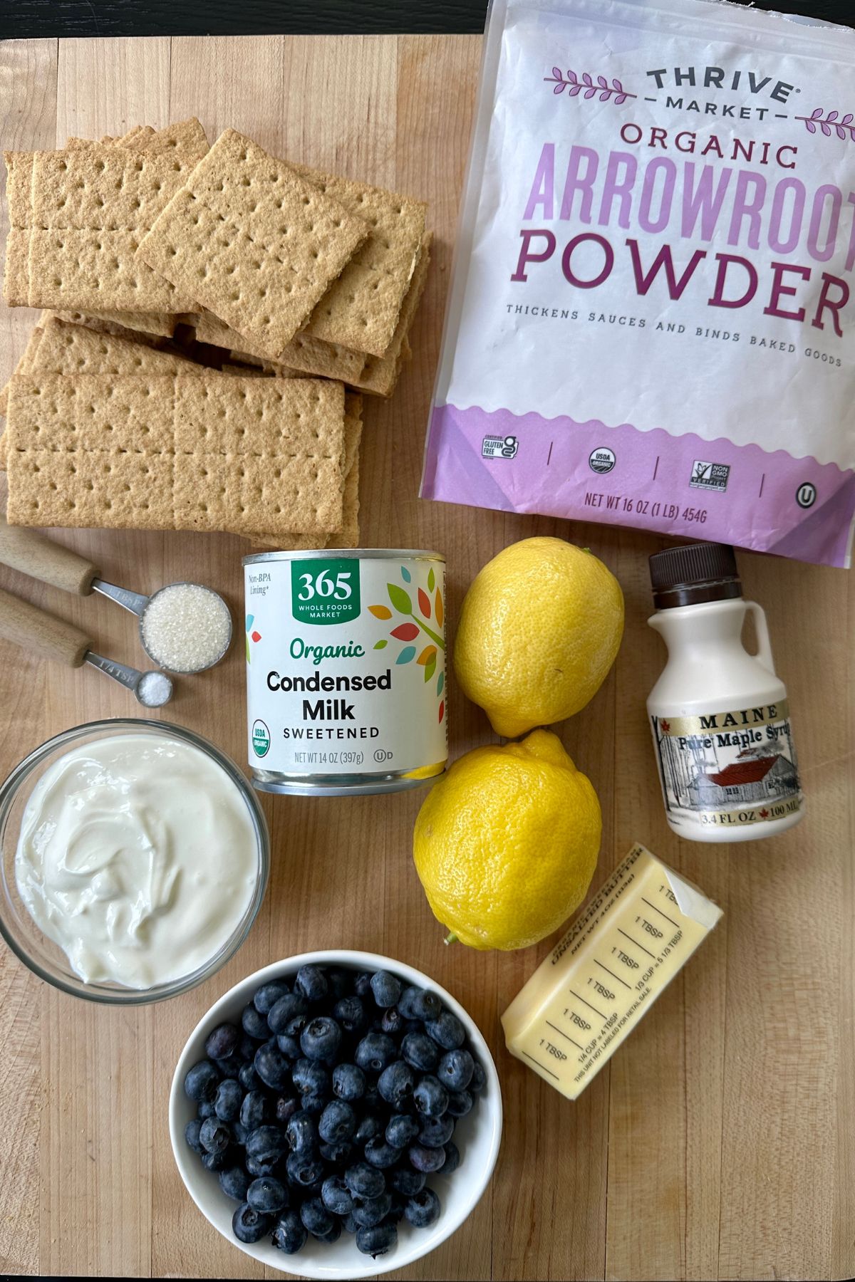 flat lay of ingredients for a blueberry lemon tart including graham crackers, blueberries, yogurt, and fresh lemons