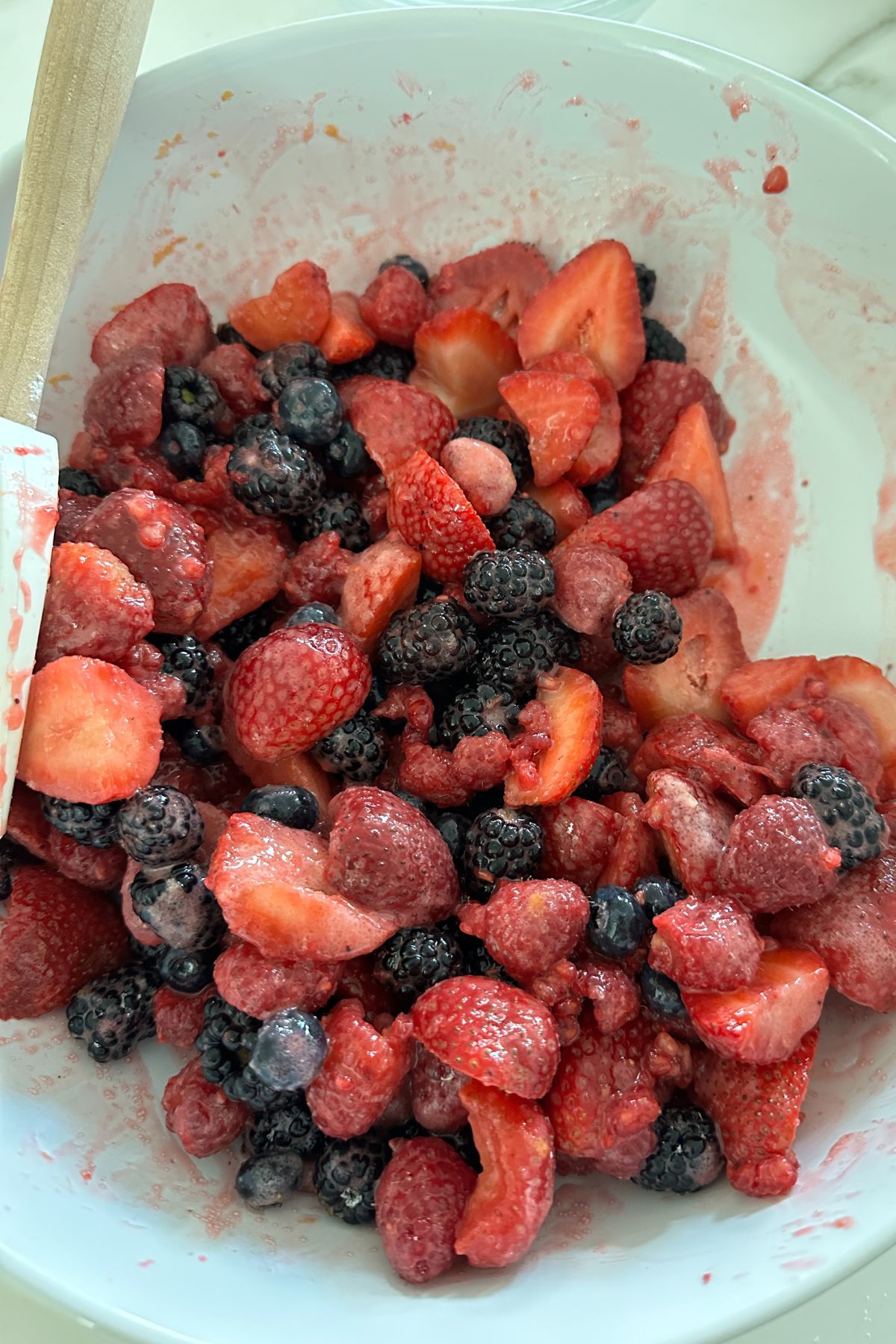 Mixed berries tossed with sugar, arrowroot, lemon zest, and lemon juice in a bowl