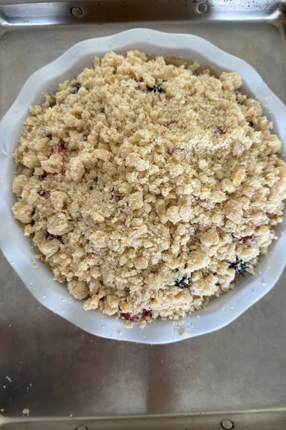 Berry filling spread in a chilled crust, sprinkled with crumb topping before baking