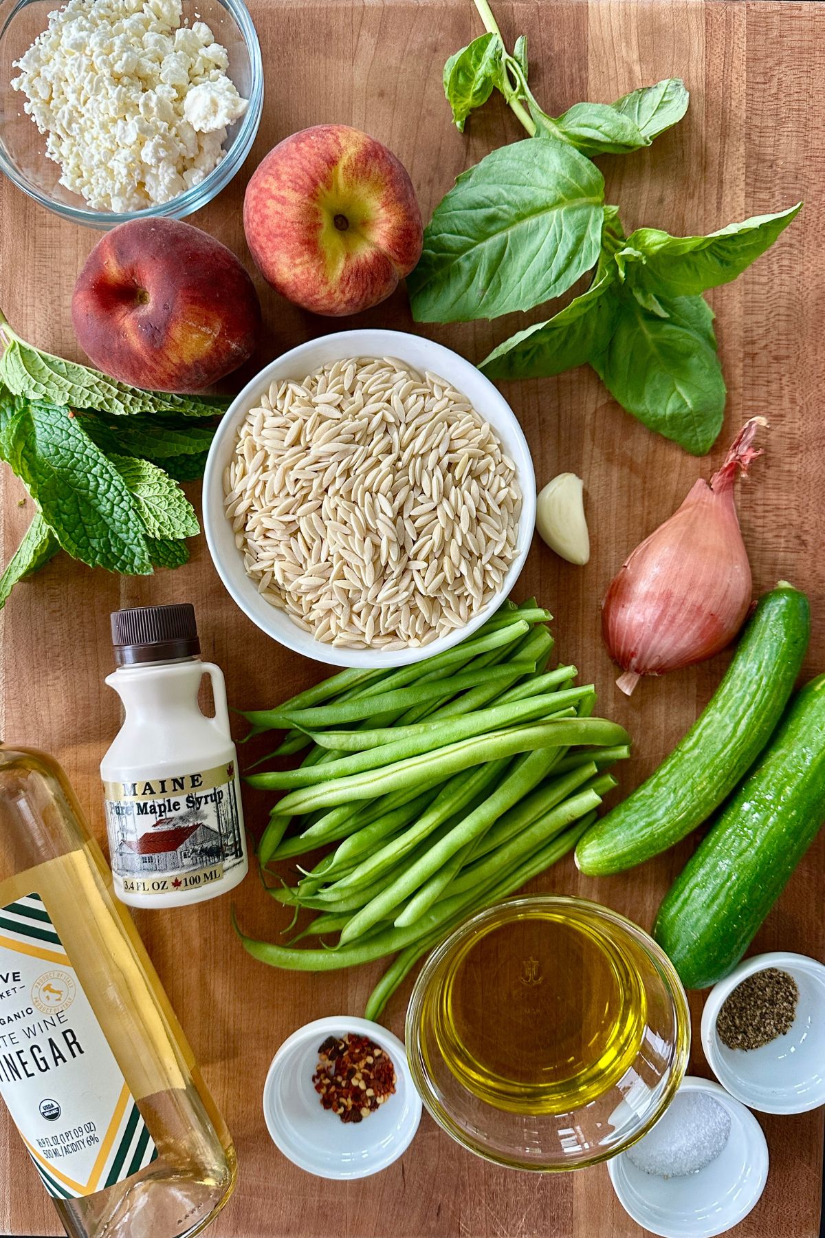 recipe ingredients for a summer orzo pasta salad resting on a cutting board. 
