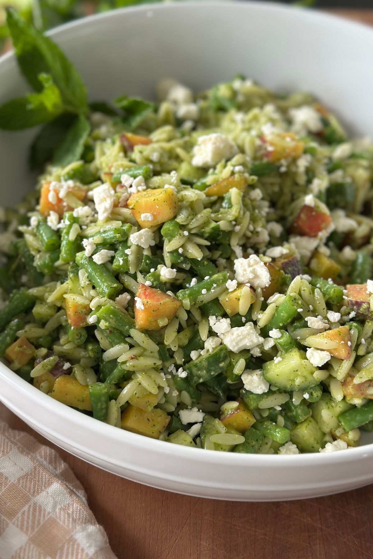 a delicious summer orzo salad tossed with dressing and placed in a white bowl ready to eat 