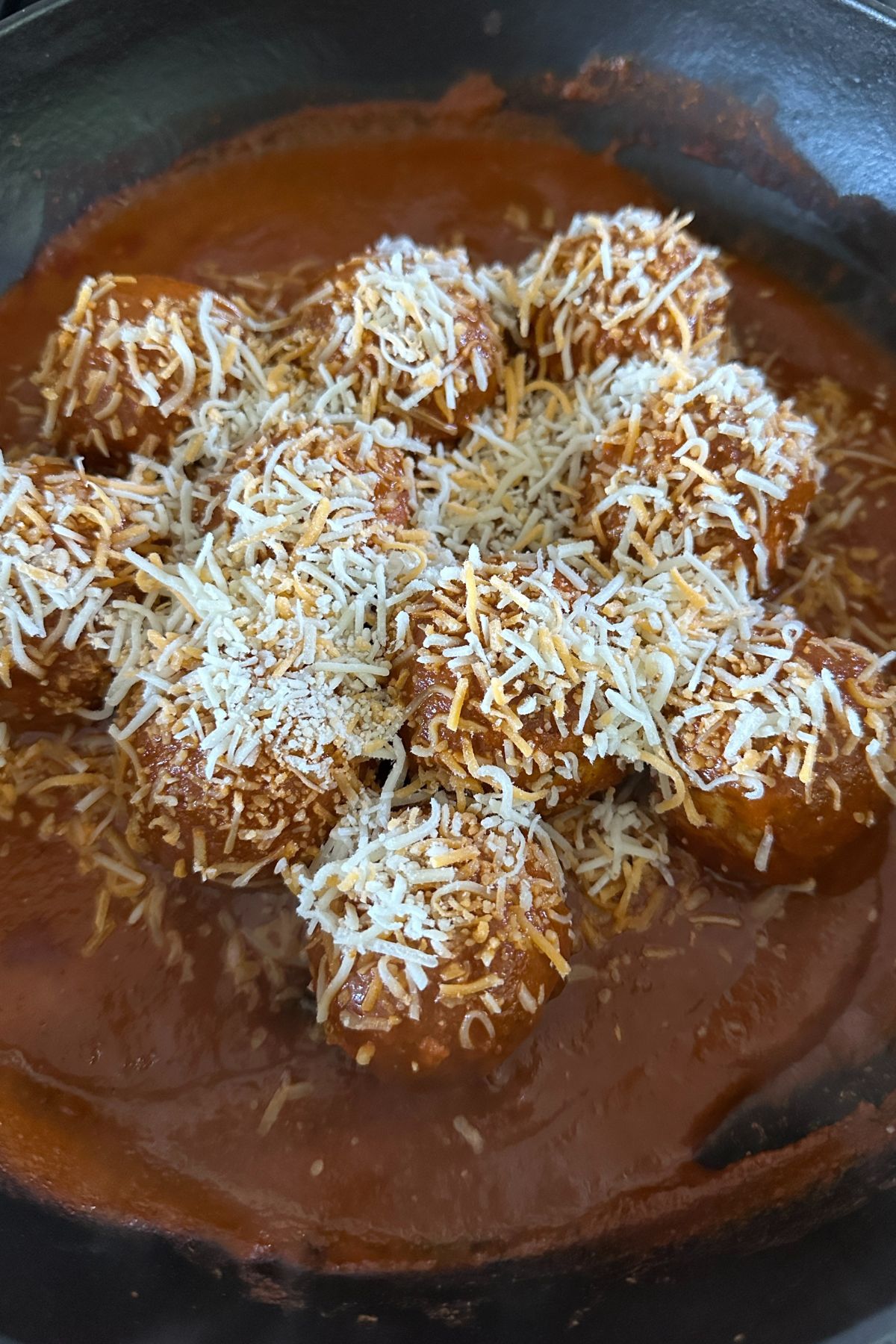 meatballs in sauce topped with cheese