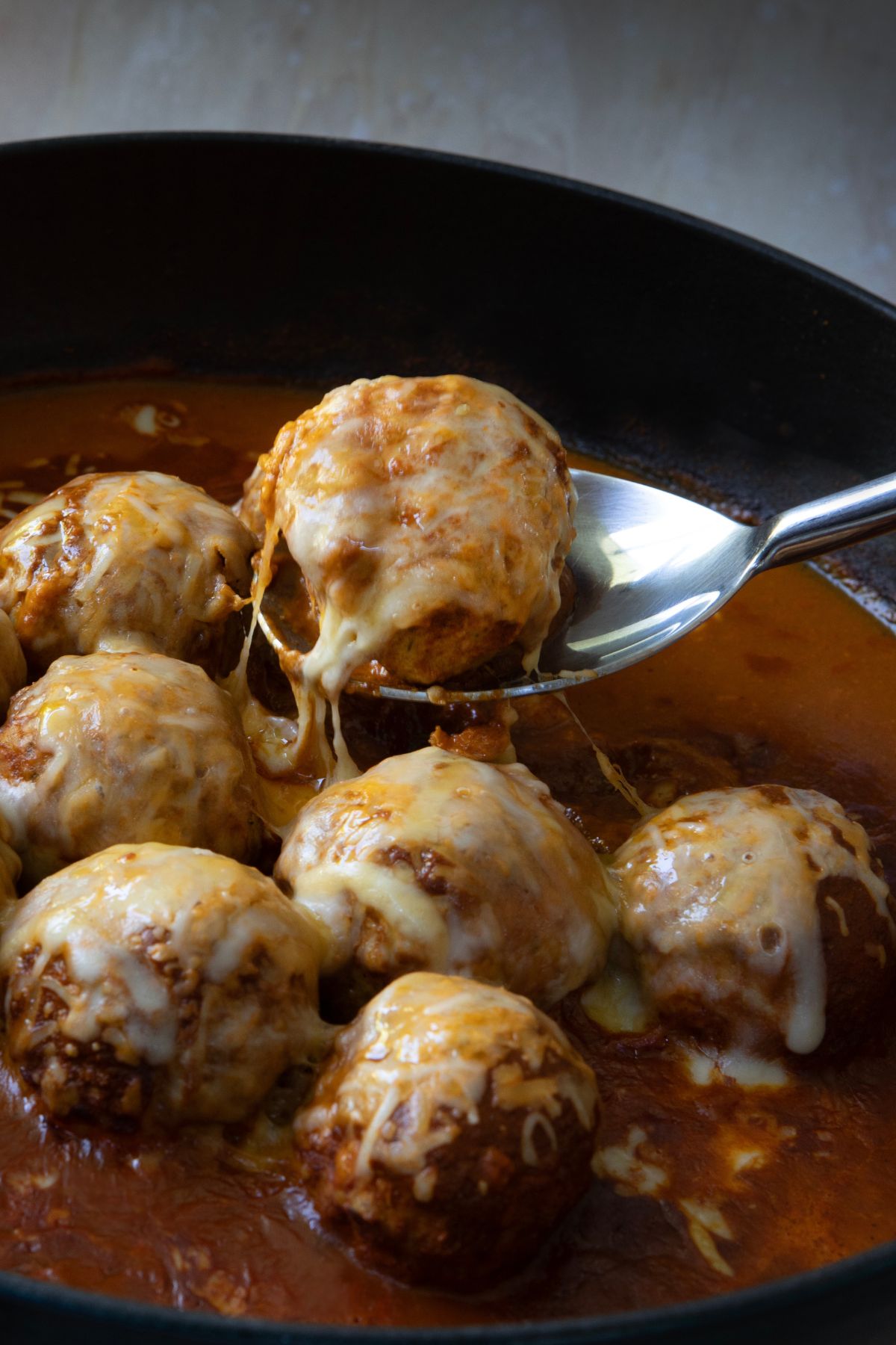 a spoon lifting a cooked tex mex meatball out of a pan