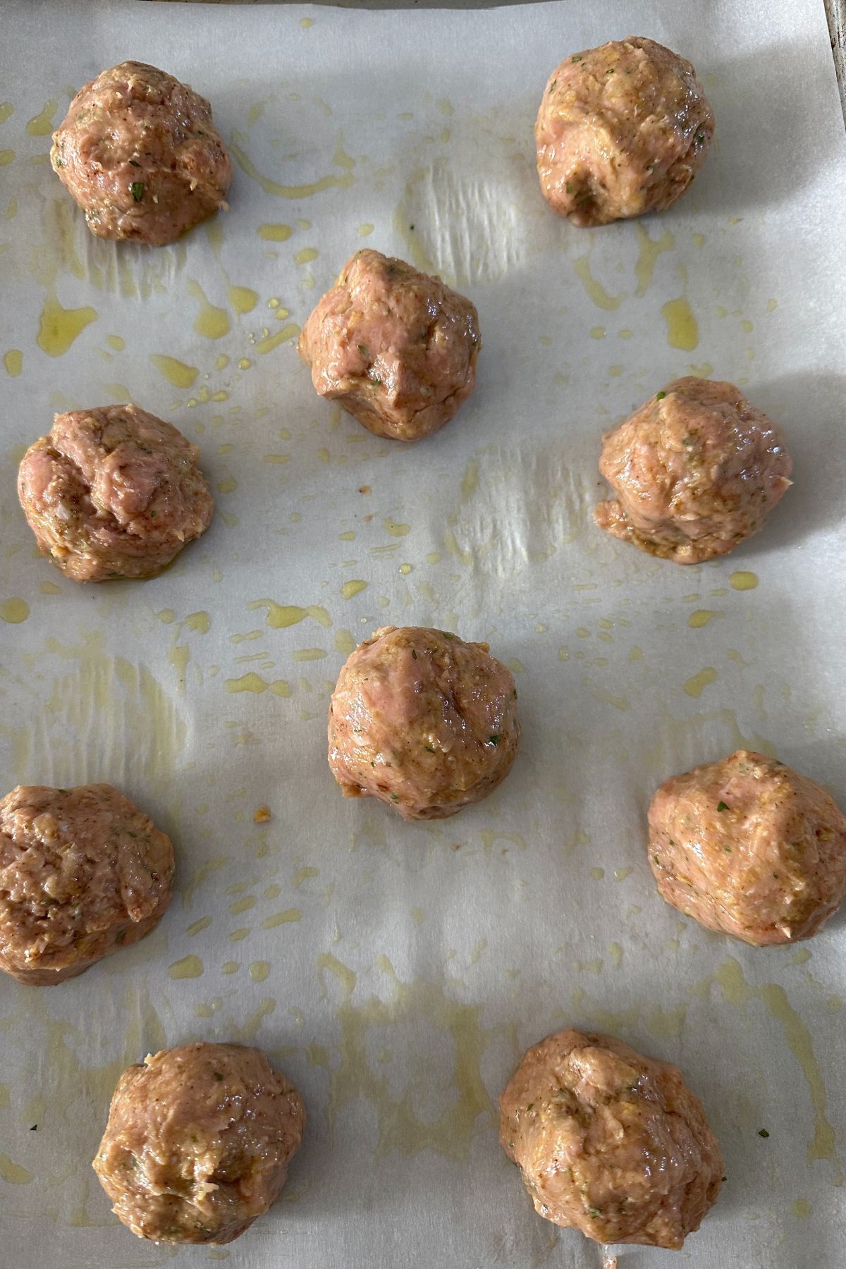 raw meatballs on a baking sheet with parchment paper