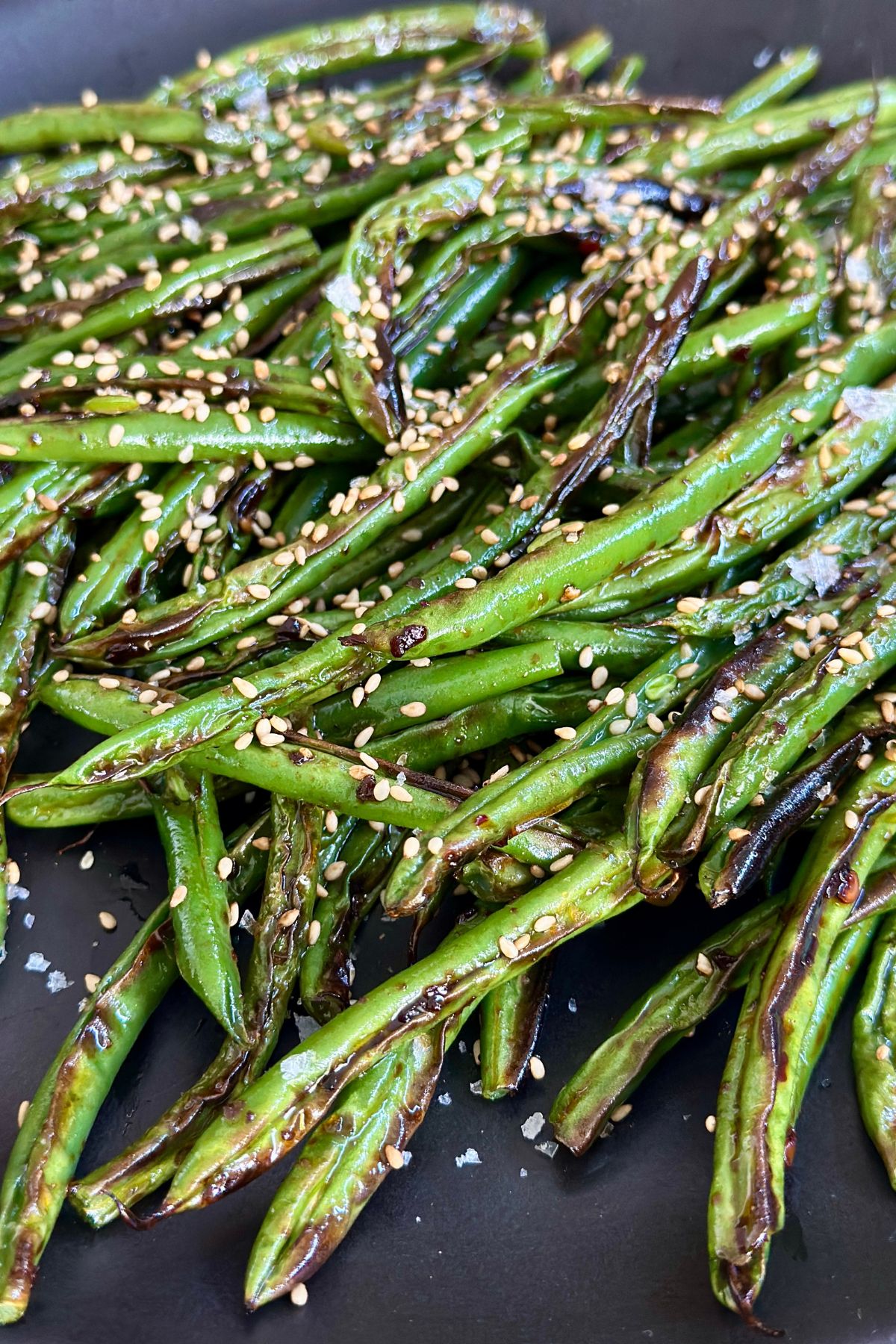 a close up shot showing the cooked green beans garnished with sesame seeds