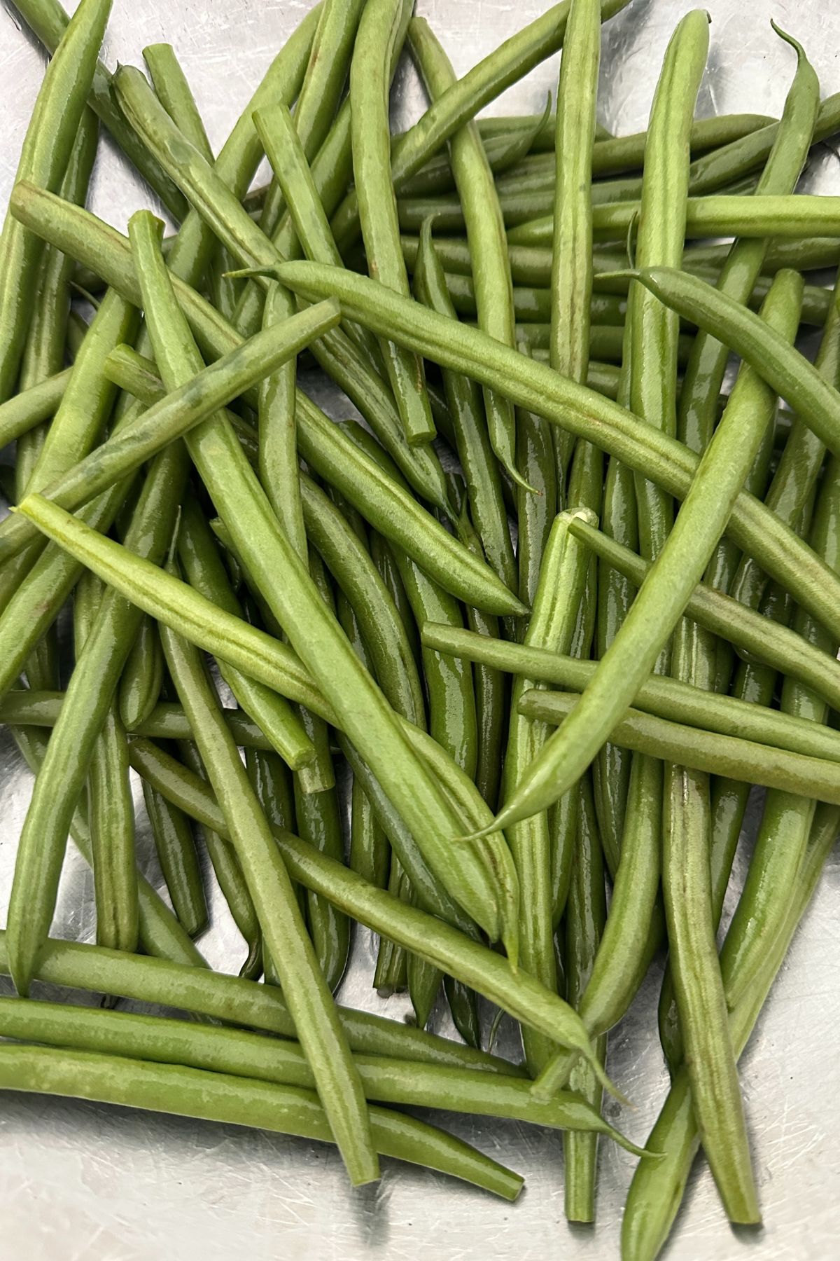 washed green beans on a white surface waiting to be trimmed