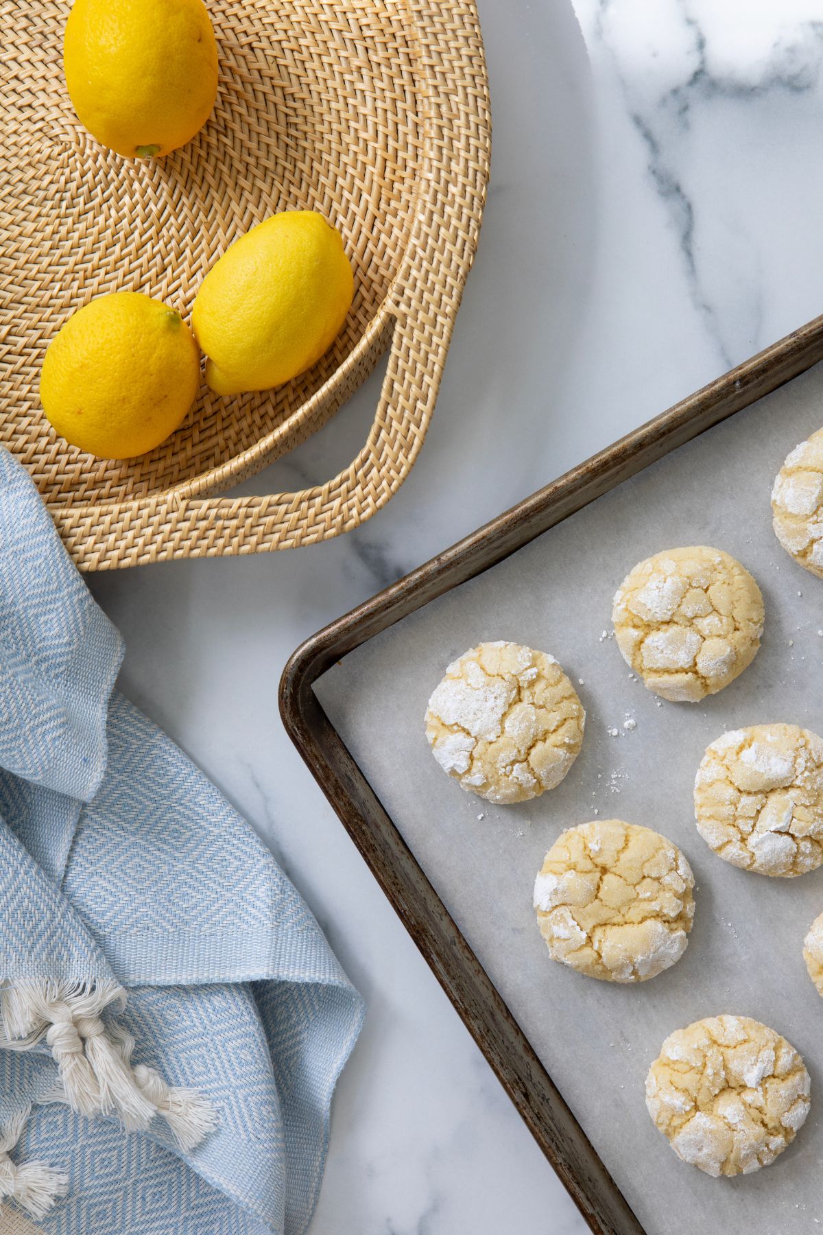 Overhead shot of lemon crinkle cookies on baking sheet with powdered sugar dusting