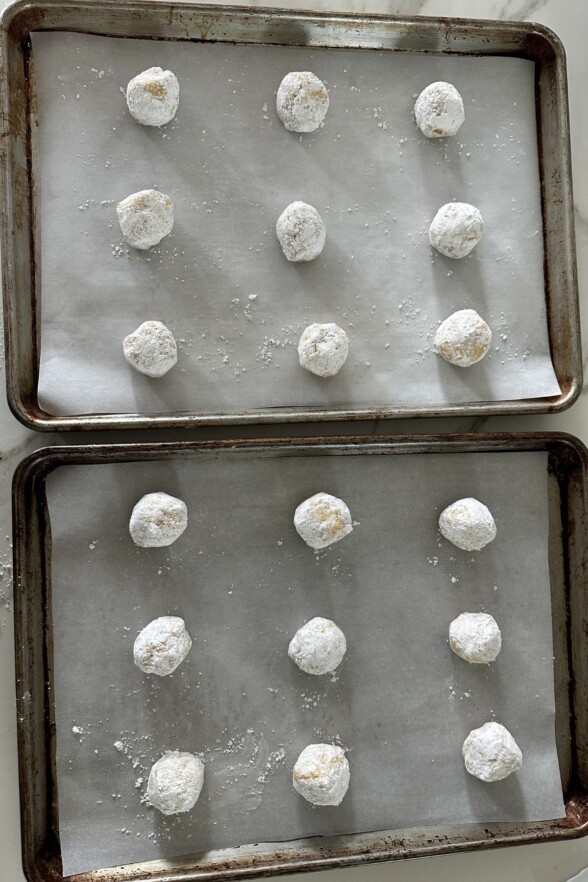 Lemon cookie dough balls rolled in granulated and powdered sugar on baking tray
