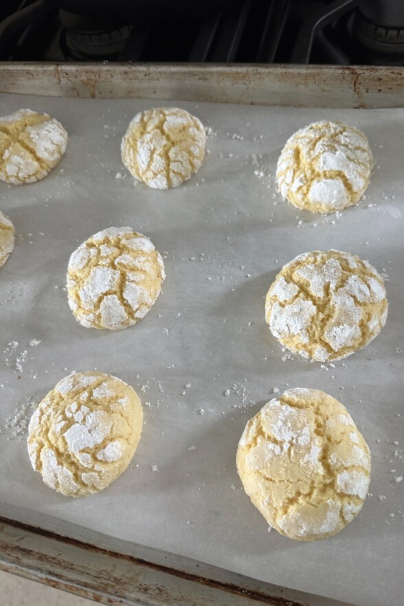 Freshly baked lemon crinkle cookies cooling on the pan