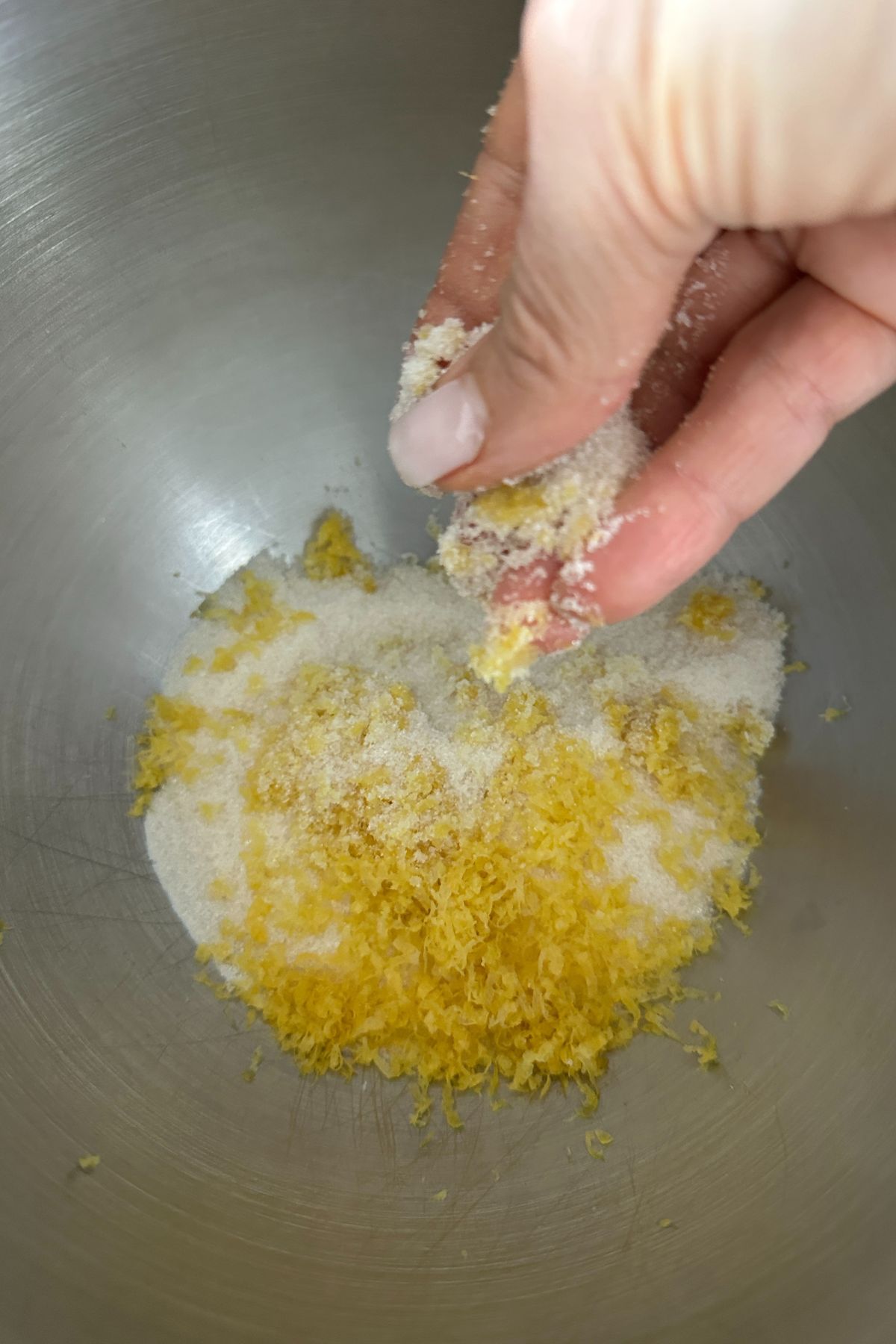 Lemon zest and sugar being mixed in a bowl to release citrus oils
