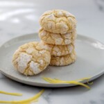 crackly lemon crinkle cookies stacked on a plate with powdered sugar tops