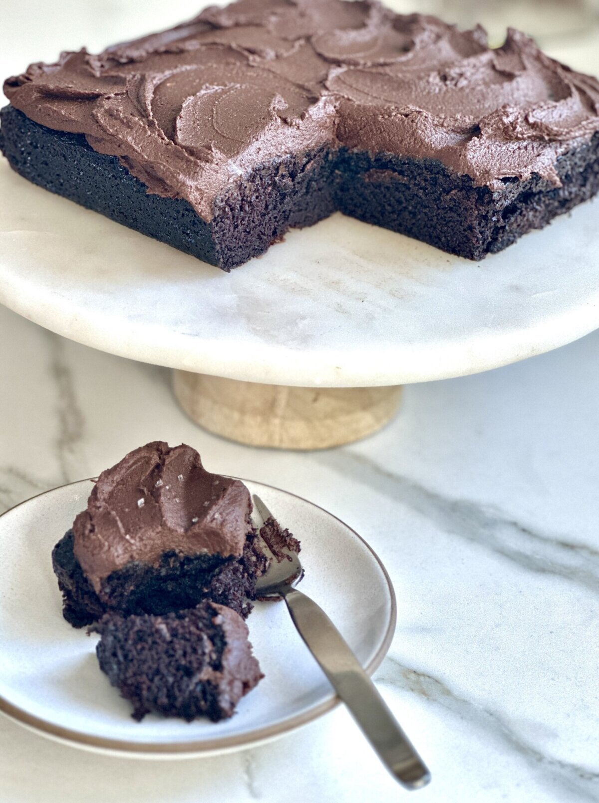 gluten-free vegan chocolate cake with sweet potato frosting on a stand and a plate with a fork