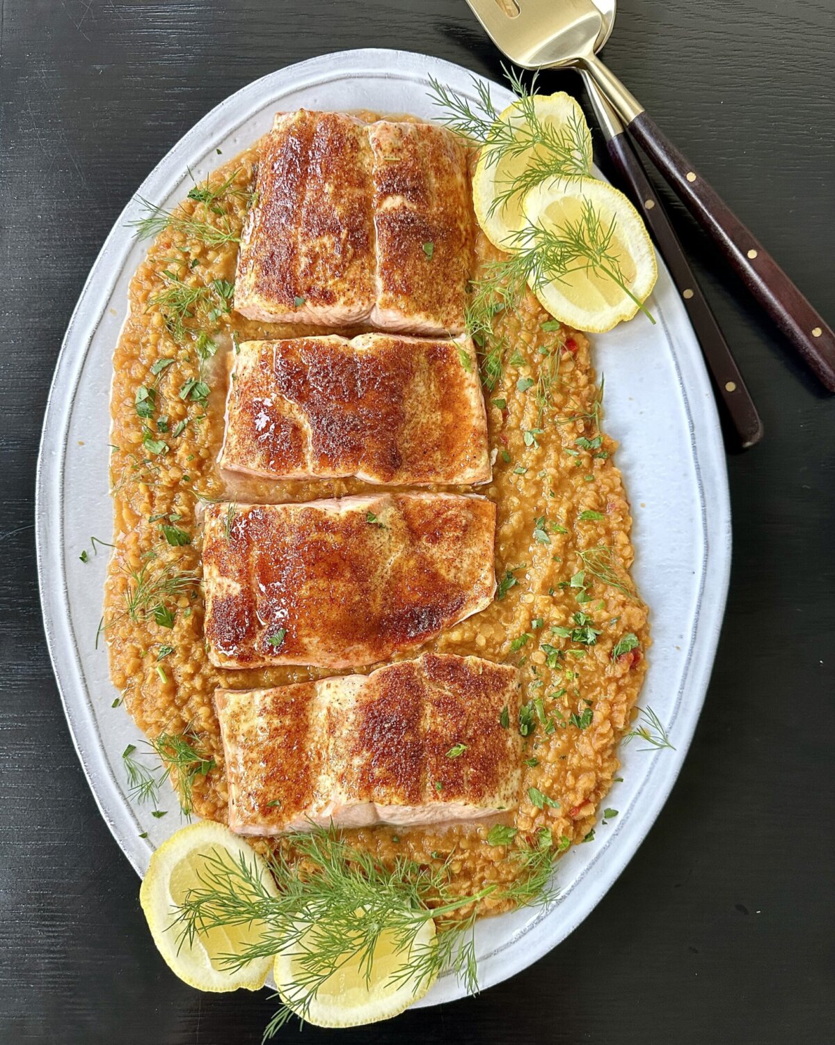 salmon over red split lentils on a white serving platter