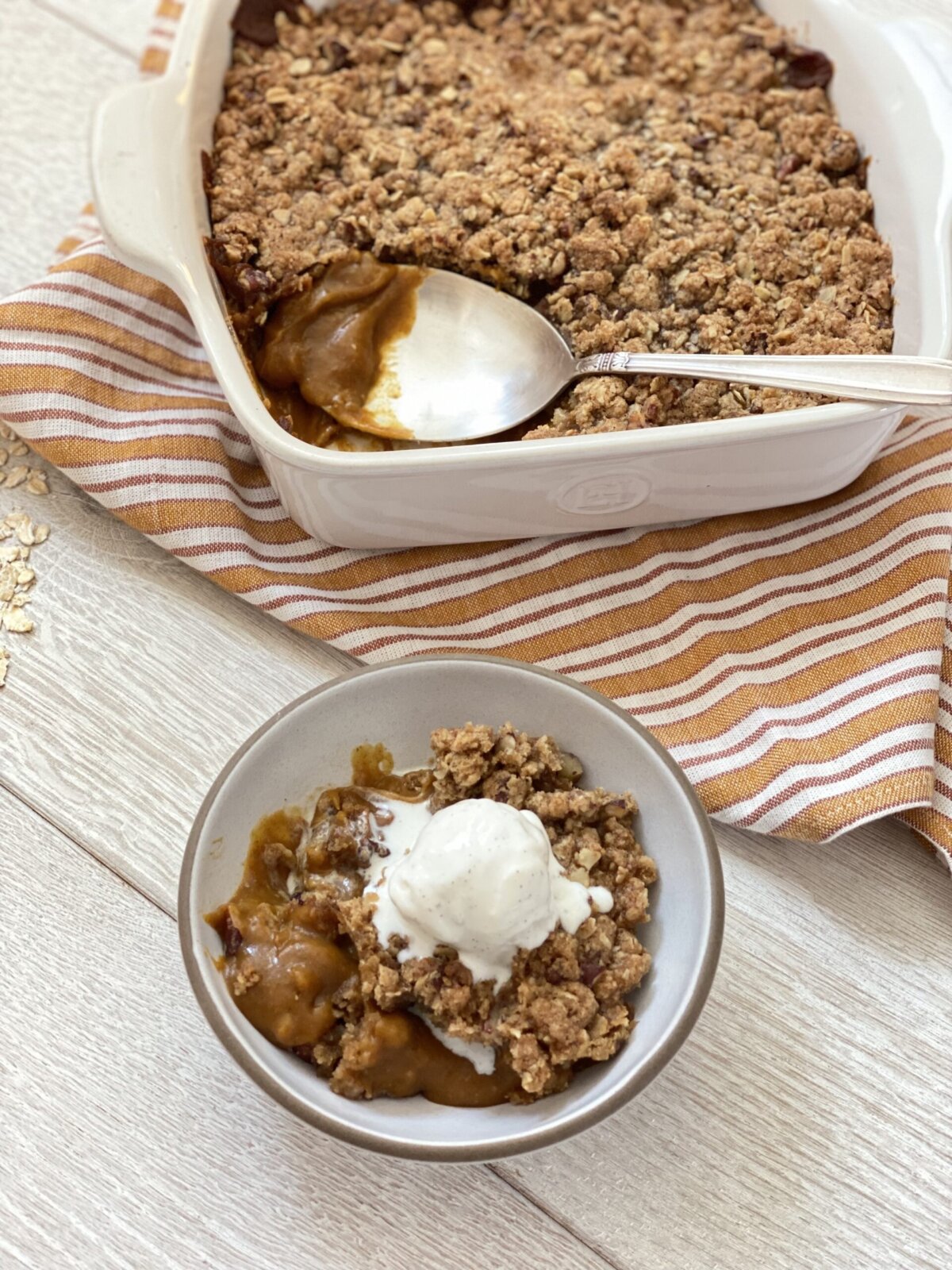 a bowl of pumpkin crisp with a scoop of vanilla ice cream on top